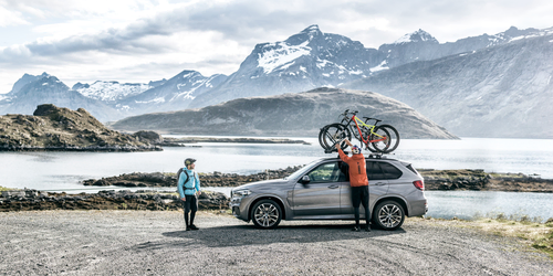 An image of two cyclists loading bikes on to the roof of a vehicle